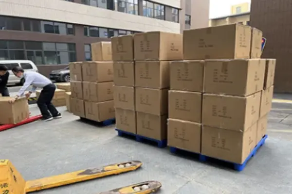 Workers packing custom golf gloves and golf head covers into secure export cartons