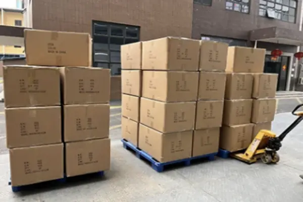 Warehouse forklift loading pallets of custom golf gloves and head covers onto truck